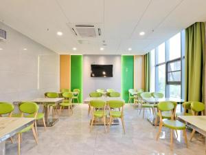 a room with tables and chairs and a flat screen tv at Vatica Hotel Hefei Yaohai Longgang Subway Station in Hefei