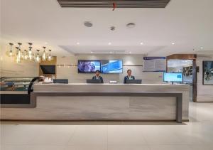a lobby with two people sitting at a counter at City Comfort Inn Shiyan High-speed Railway Wanda Plaza in Shiyan