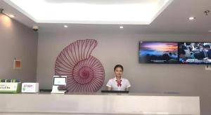 a woman sitting at a counter with a laptop at Shell Hotel Shanghai Minhang District Wenjing Road Metro Station in Shanghai