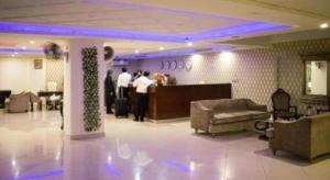 a lobby with people standing at a counter in a building at Hotel Grand Millennium in Lahore