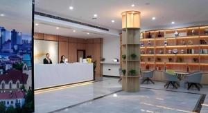a lobby with two people at a counter in a building at GreenTree Inn Express Shandong Qingdao Chengyang District Aodong Road in Qingdao