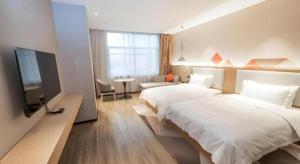 GuzhutingにあるBorrman Hotel Yongzhou High Speed Railway Stationのベッド2台と薄型テレビ付きのホテルの部屋