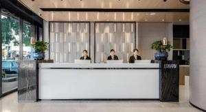 three people sitting at a reception desk in a lobby at Echarm Hotel Changsha Wuyi Square Xiangya 2nd Hospital Metro Station in Changsha