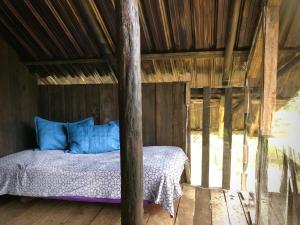 een bed met blauwe kussens in een houten hut bij Finca MamaChakra - Cabañas - Camping in Cumandá