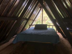 a bed in a wooden room with a window at Finca MamaChakra - Cabañas - Camping in Cumandá