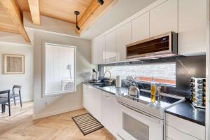 a kitchen with white cabinets and a large window at Stay Portland - Alberta Arts Escape - Modern 3BR Townhome in Portland