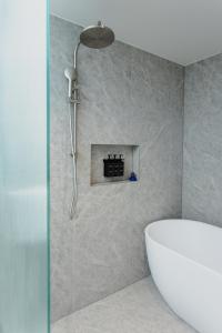 a bathroom with a shower and a white tub at Bayside Geelong Hotel & Apartments, an Ascend Collection Hotel in Geelong