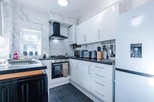a kitchen with white cabinets and black appliances at 3 BR House By By Eason Stays Short Lets & Serviced Accommodation Sheffield With Pool Table & Free Parking in Nether Edge