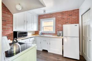 een keuken met witte kasten en een bakstenen muur bij Cozy Boho 1BR - Walk to Shops & Cafes in Portland