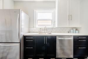 a kitchen with black cabinets and a stainless steel refrigerator at Stay Portland - Alberta Arts Haven - 2BR - 4 Guests - Walk to Eats in Portland
