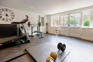 a room with a gym with a treadmill and a clock at 6 BR Luxury House With Huge Garden and Cinema Room By Eason Stays Short Term Rental Rugby in Long Lawford