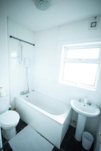 a white bathroom with a toilet and a tub and a sink at 3 BR House Near Beach By Eason Stays Short Lets & Serviced Accommodation Lowestoft in Lowestoft