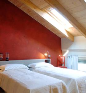 two beds in a room with a red wall at Corte Mondina in Gazoldo degli Ippoliti
