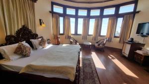 a bedroom with a large bed and large windows at Hotel Padmini NIvas in Mussoorie