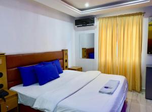 a bedroom with a large bed with blue pillows at PnK Inn in Adeleye