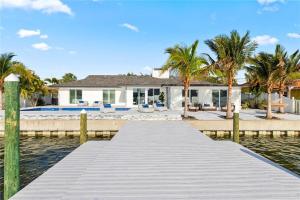 a dock leading to a house on the water at Waterfront l Private Pool l Dock l Sunset Views in St Petersburg