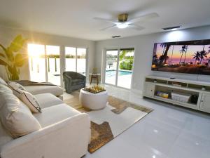 a living room with a white couch and a flat screen tv at Waterfront l Private Pool l Dock l Sunset Views in St Petersburg