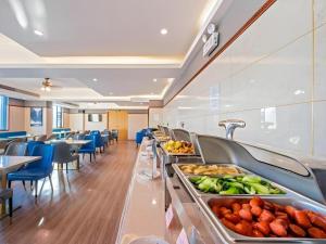 a buffet line in a restaurant with tables and chairs at Green Tree Inn Zhuhai International Airport Huafa Shangdu in Baigaonongchang
