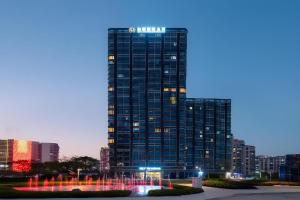 a tall building with a fountain in front of it at Poltton International Service Apartment Shanwei Urban District High-speed Railway Station in Shanwei