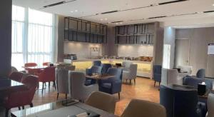 a restaurant with tables and chairs in a room at Echarm Hotel Yantai Wuzhou International in Yantai