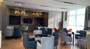a lobby with chairs and tables and a television at Echarm Hotel Yantai Wuzhou International in Yantai