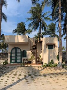 a house on the beach with palm trees at LAWA Bintan Berakit Village Cottage in Berakit
