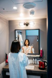 a woman standing in front of a bathroom mirror at Moxy Osaka Umeda in Osaka