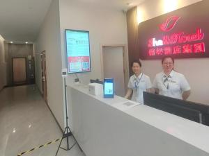 two women standing at a counter in a restaurant at Shell Hotel Wuxi Huishan District Chang'an Town in Wuxi