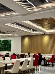 a conference room with white tables and red chairs at J HOTEL in Kampong Kiulap