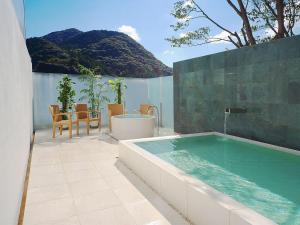 a hot tub on a patio with a table and chairs at Yamamura Bekkan in Nagato