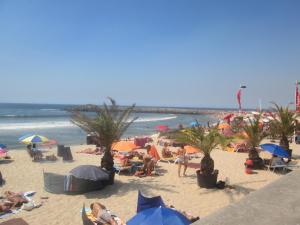 eine Gruppe von Menschen am Strand mit Sonnenschirmen in der Unterkunft Why Not? Guest House Espinho in Espinho