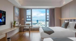 a hotel room with a bed and a large window at Gya Hotel Kunming Zijin Center Xiaodongcun Metro Station in Kunming