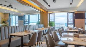 a restaurant with tables and chairs and large windows at Gya Hotel Kunming Zijin Center Xiaodongcun Metro Station in Kunming