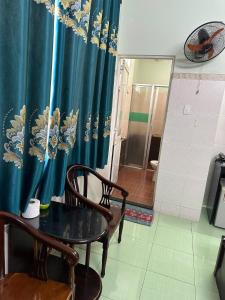 Giang Phuoc Hung hotel في مدينة هوشي منه: غرفة بطاولة وكراسي وستارة زرقاء