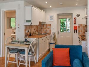 a kitchen and living room with a blue couch at Kingfisher Cottage, 20 in Camelford