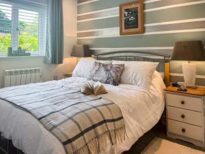 a bedroom with a bed with a book on it at Kingfisher Cottage, 20 in Camelford +14 photos