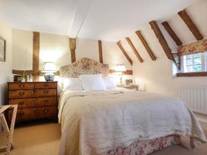 a bedroom with a bed and a dresser and two windows at Lynchets Cottage in Lambourn