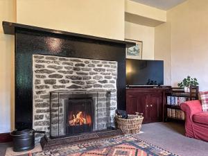 a stone fireplace in a living room with a red couch at High Rylands in Arncliffe