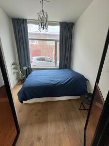 a bedroom with a blue bed and a window at Cozy apartment in Utrecht in Utrecht