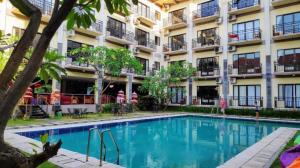 a hotel with a swimming pool in front of a building at The Aroma's of Bali Hotel & Residence in Legian