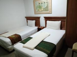 two beds in a hotel room with white sheets at J Hotel Bukit Bintang in Kuala Lumpur +4 photos