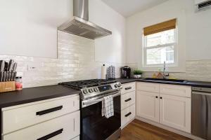 a kitchen with white cabinets and a stove top oven at Stay Portland - The Câlin Suite - Posh Local Boutiques & Eateries in Portland +12 photos