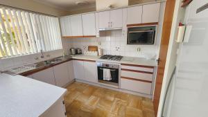 une cuisine avec des armoires blanches et un four à plaques de cuisson dans l'établissement Hello House, à Safety Bay