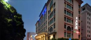 een hoog roze gebouw met lichten aan de zijkant bij Shenzhen Hanyong Hotel Fuyong Branch in Fenghuangwei
