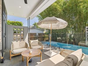 een terras met stoelen en een parasol en een zwembad bij Serenity & Poolside Sun - 400m to Beach in Scarborough