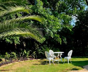 three white chairs and a table in the grass at De Kaapse Rust Guesthouse & Venue in Parys