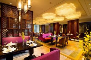 a restaurant with purple furniture and tables and chairs at New Century Grand Hotel Hangzhou Zheshang in Yuhang