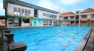 a swimming pool at a resort with blue water at Umah Bali Suites in Denpasar