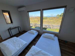 2 Betten in einem Zimmer mit 2 großen Fenstern in der Unterkunft レイクウエスト4-711 in Wada