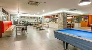 a pool table in a large room with tables and chairs at Royal Bay Hotel Makassar in Makassar